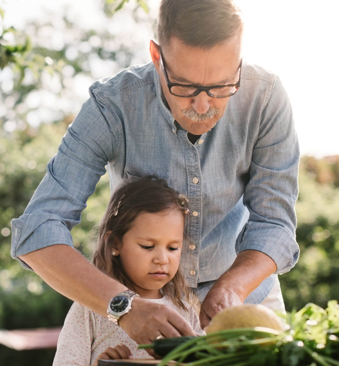 A grandfather gardening with his granddaughter