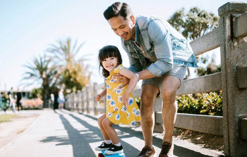 A father helping his young daughter skateboard